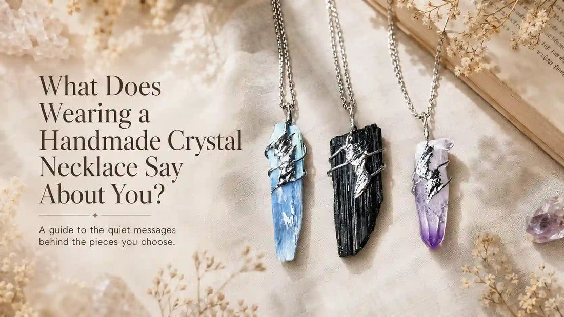 Three handmade crystal necklaces — kyanite, black tourmaline, and amethyst — styled on soft neutral fabric with dried flowers and warm natural light beside the blog title “What Does Wearing a Handmade Crystal Necklace Say About You?”