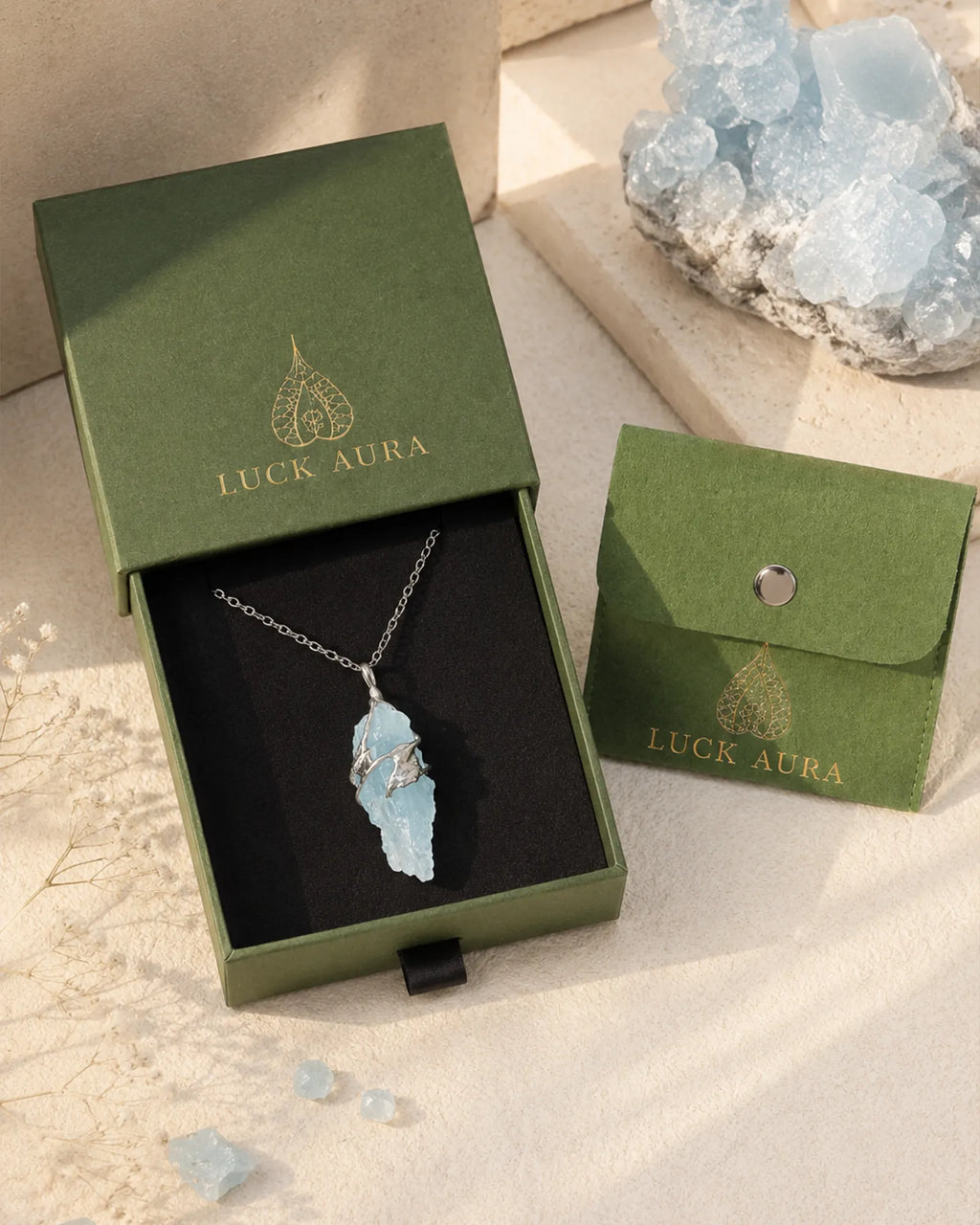 Handmade glacial blue crystal necklace displayed with LuckAura gift packaging, dried flowers, and soft natural light as a meaningful jewelry gift.