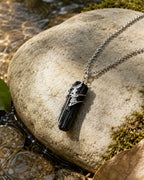 Black tourmaline soldered pendant necklace styled in a calm natural setting with stone, soft light, and a grounding handmade crystal jewelry aesthetic.