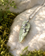 Green crystal soldered pendant necklace styled in a calm natural setting with moss, stone, soft light, and a nature-inspired handmade jewelry aesthetic.