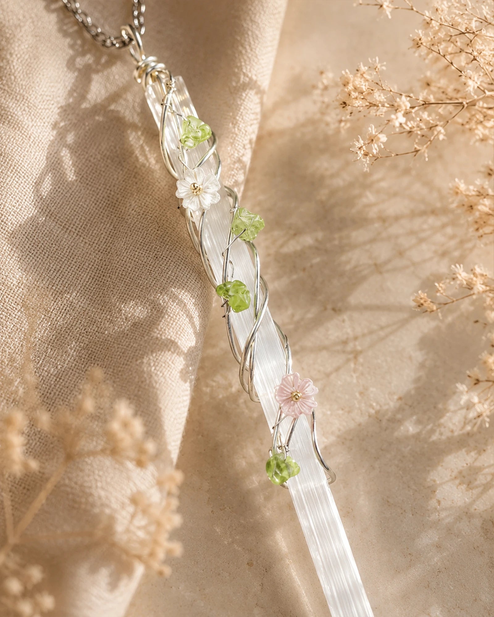 Close-up of handmade selenite garden wire wrapped pendant showing natural crystal texture, delicate wire wrapping, and floral accent details.