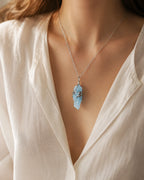 Woman wearing a handmade glacial blue crystal necklace, styled as meaningful crystal jewelry for calm, clarity, and peaceful energy.